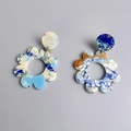 Dettaglio di orecchini a fiore in acrilico con texture marmorizzata blu e ambra - Blu