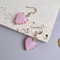 Nahaufnahme der durchsichtigen rosa Herz-Ohrringe mit roten Details und Goldhaken - Gold-Rosa