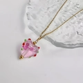Detail van roze glazen hartvormige hanger aan gouden ketting op een ijsstructuur blad - Goud-Transparant Roze