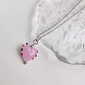 Detailopname van roze glazen hartvormige hanger met kleurrijke stippen op zilveren ketting - Staal-Roze