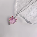 Detail van roze hartvormige hanger met roos en gekleurde stippen aan een zilveren ketting - Zilver-Transparant Roze
