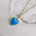 Dettaglio del ciondolo a cuore in vetro blu con accenti gialli su catena in oro inox - Oro-Azzurro