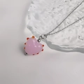 Gros plan du pendentif cœur en verre rose avec pointes orange sur chaîne argentée - Acier-Rose