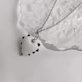 Gros plan détaillé du pendentif cœur blanc à pois noirs sur une chaîne en acier argenté - Acier-Blanc