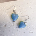 Blaue Herz-Ohrhänger mit gelben Punkten auf einem schlichten weißen Steinsockel - Stahl-Himmelblau