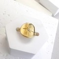 Top view of gold starburst signet ring with zircon on a white geometric display stand - Gold