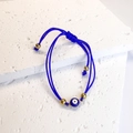 Dettaglio del bracciale occhio di Allah intrecciato blu con perline dorate su pietra bianca - Blu
