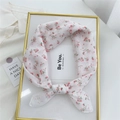 White linen scarf with small pink floral print tied in a bow on a white display tray - Red Wildflower