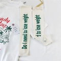 Detail of white sun protection arm sleeves with finger holes and green text print - Off White