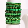 Set di bracciali bohémien con perline di legno verdi di varie forme su supporto bianco - Set da 13 pezzi verde