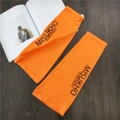Detail of bright orange sun sleeves with adjustable buckle and letter print on wooden surface - Orange with Black Letter