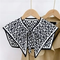 Detail of a black and white geometric shawl collar with letter C ring and bow tie closure - Rhombus Color Block C Black (10F)