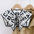 Close-up of geometric print silk scarf shawl with bow tie on a khaki trench coat - Letter Plaid Black Grey (18F)