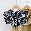 Detail of black and white camellia print shawl wrap tied over a tan trench coat - Big Flower Small Plaid Black (19F)