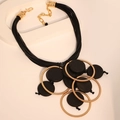 Detail view of multi-layer cord necklace with golden metal rings and black wooden pendants - Necklace