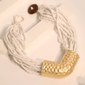 Detail van meerlaagse witte kralenketting met getextureerd goudkleurig metaalaccent - Wit