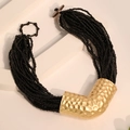 Detail van de meerlaagse zwarte kralenketting met goudgehamerde metalen hangers en knop - Zwart
