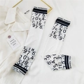Detail of white cooling arm sleeves featuring black numerical prints and Doria Dore text - Digital Edge