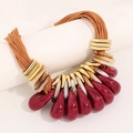 Close-up of bohemian layered necklace with amber resin petals and gold accents - Red