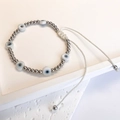 Detail of adjustable evil eye bead bracelet with silver beads and white woven cord - Steel-White