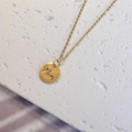 Macro view of gold MOM pendant necklace on textured stone background with detailed engraving - Gold