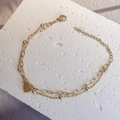 Detail of double-layer gold heart bracelet on a white stone with lobster clasp closure - Gold - Heart