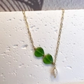 Detail of Y-shaped gold necklace featuring twin green hearts and a baroque pearl drop - Green