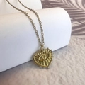 Detalle de collar con colgante de corazón dorado con ojo turco y diseño solar - Collar de Corazón / Dorado