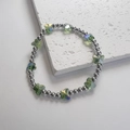 Dettaglio macro di perle a farfalla in vetro bohémien con finitura cangiante effetto aurora - Farfalla Verde / Argento-Verde