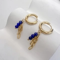 Dettaglio di orecchini a cerchio dorati con perle blu lapislazzuli e maglie in metallo - Lapislazzuli