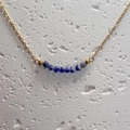 Macro view of gold chain necklace featuring blue natural stone beads on stone background - Blue Spot Jasper