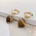 Detalle de pendientes de corazón en ojo de tigre y aros dorados sobre mármol - Ojo de tigre