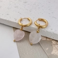 Primer plano de pendientes de aro dorados con colgantes de corazón en piedra natural rosa - Cuarzo rosa