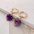 Close-up of heart-shaped purple stone earrings with elegant gold accents on a stone - Amethyst