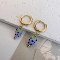 Macro-opname van gouden oorringen met handgemaakte blauw gestippelde glazen aardbeien - Wit en Blauw