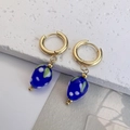 Macro detail van de aardbei oorbellen met blauwe bessen en gouden ringen op steen - Blauw