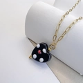Detail of black glass heart pendant with polka dots on a gold stainless steel chain - Black