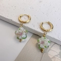 Detailed close-up of handmade glass flower earrings with gold leaf on a stone background - White Flower with Gold Foil and Dots / White