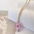 Dettaglio del ciondolo a fiore in vetro rosa su una collana a catena in acciaio inossidabile - Rosa