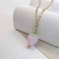Detailed view of a purple glass raspberry pendant on a gold rectangular link chain - Pink