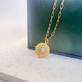Detailed macro of a gold sunburst pendant necklace with a white marbled stone inlay - Gold-White Turquoise