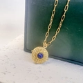 Detail of gold starburst pendant necklace with blue gemstone on a luxury display - Gold-Lapis Lazuli