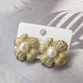 Close-up of golden frosted flower earrings with central pearl on a white display card - Gold