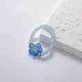 Dettaglio anello elastico con perline azzurre e ciondolo a fiore con accenti dorati - Blu