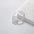 Nahaufnahme eines handgefertigten Perlenrings mit weißer Blume und goldenen Details - Weiß