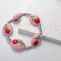 Dettaglio di perle a tulipano rosa e distanziali in argento su un bracciale in acciaio - Rosa