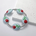 Vista macro di perle blu dipinte con fiori e perle d'argento sul bracciale elastico - Azzurro