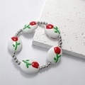 Dettaglio del bracciale con perle a tulipano con sfere argentate e tocchi floreali - Bianco