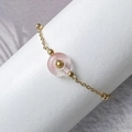 Détail d'un bracelet doré avec pierre rose et billes sur un support blanc pur - Quartz rose