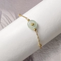 Macro detail of gold-plated titanium steel bracelet featuring a green natural stone charm - Green Aventurine